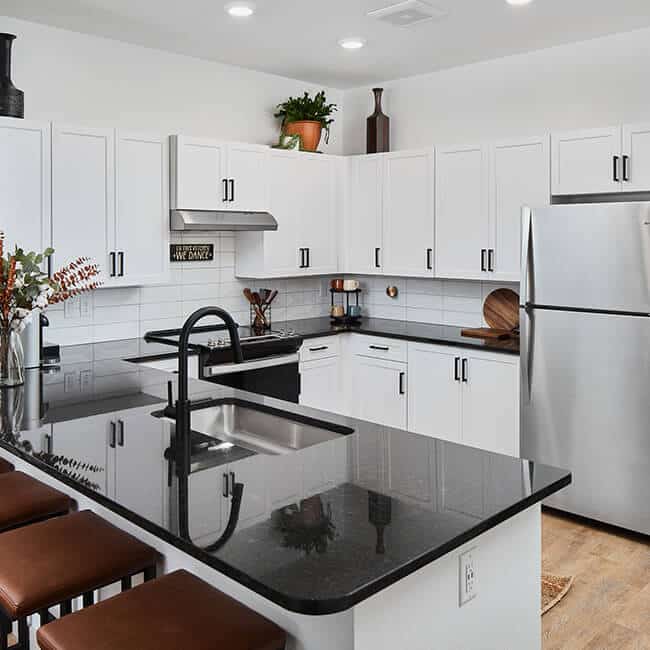 A modern apartment kitchen with black counters and white cabinets