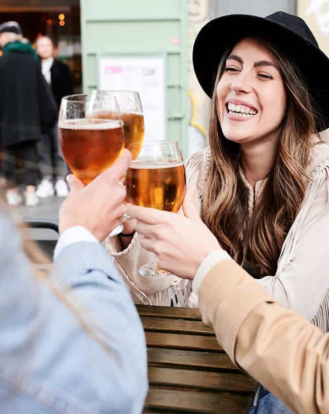 A woman enjoying craft beer outside with a group of friends